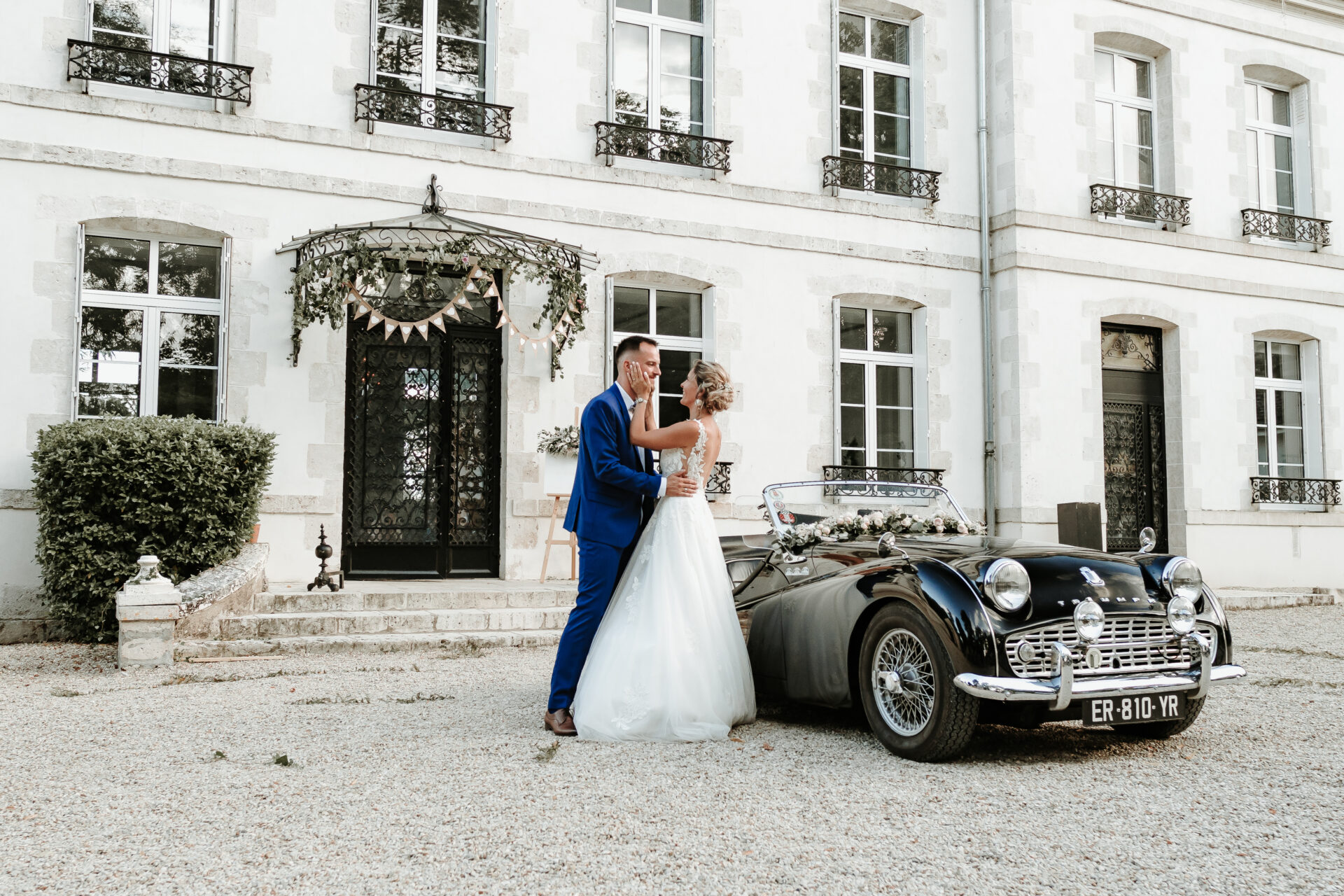 Mariés s'embrassant devant un château avec voiture de collection, photographe mariage région Centre
